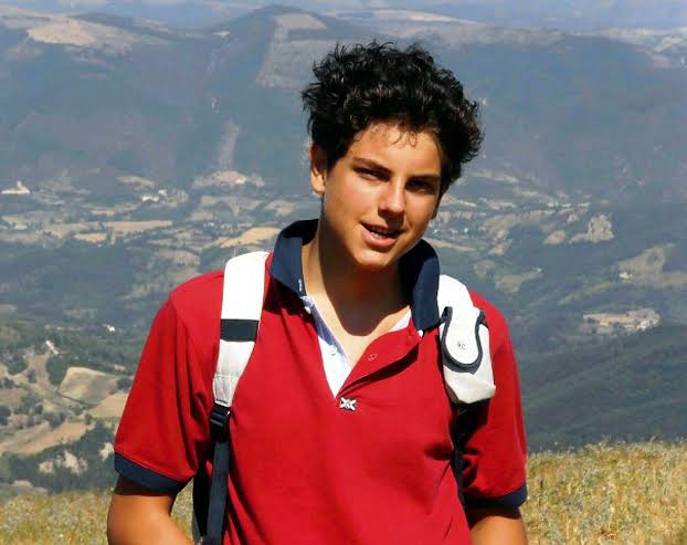 Youth standing outdoors with a mountain landscape behind him